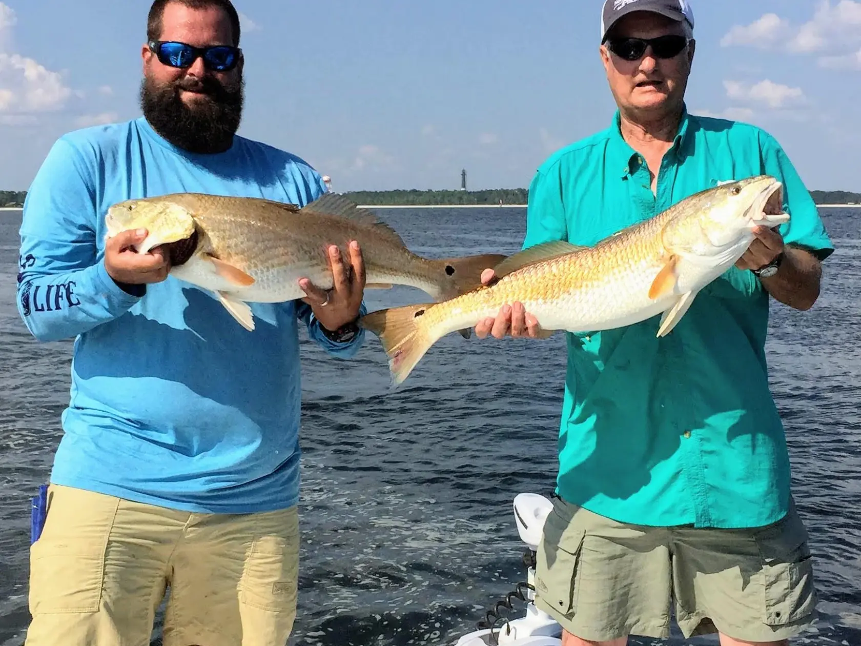 Two men holding up fish they caught in the Gulf of Mexico