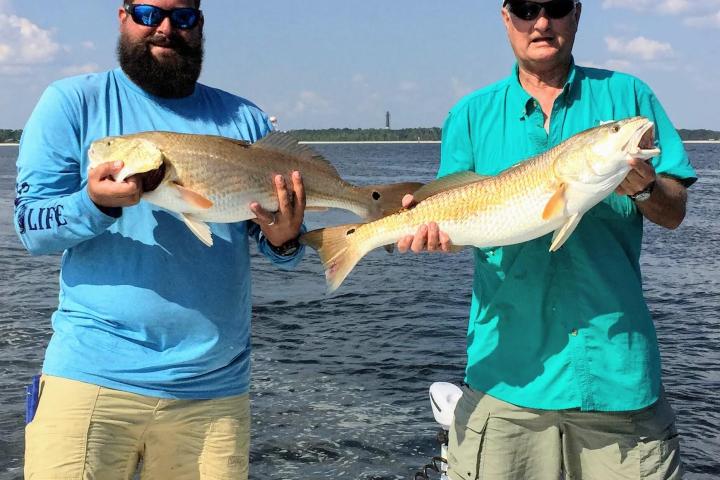 Two men holding up fish they caught in the Gulf of Mexico