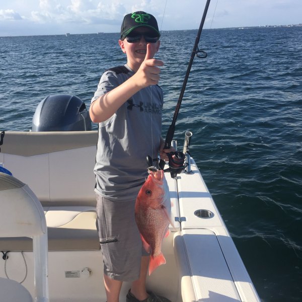 Boy holding up red snapper he just caught