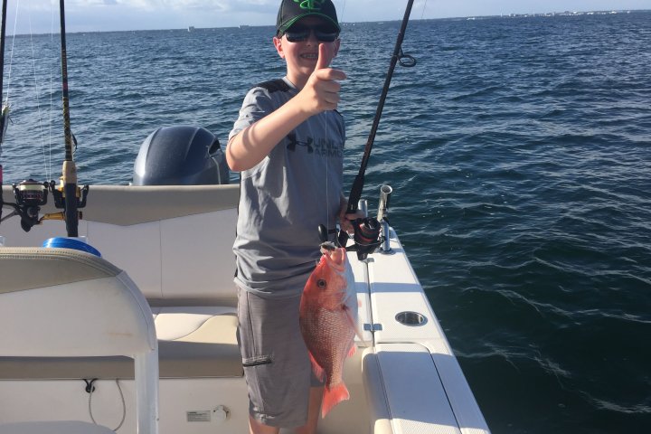 Boy holding up red snapper he just caught