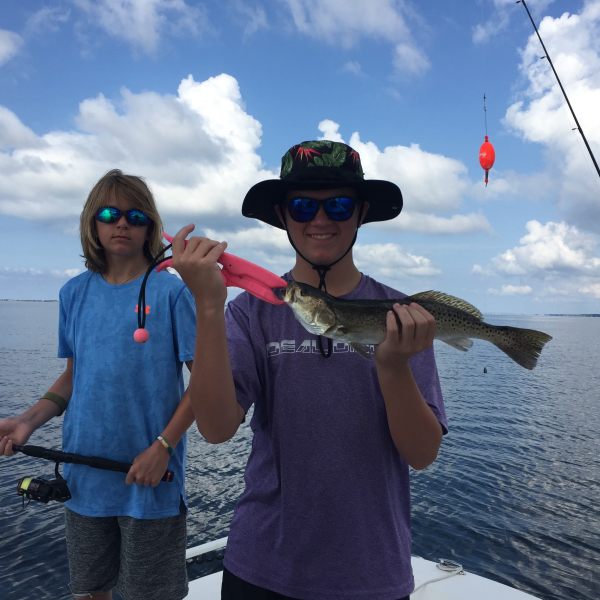 Man holding up fish standing on a boat