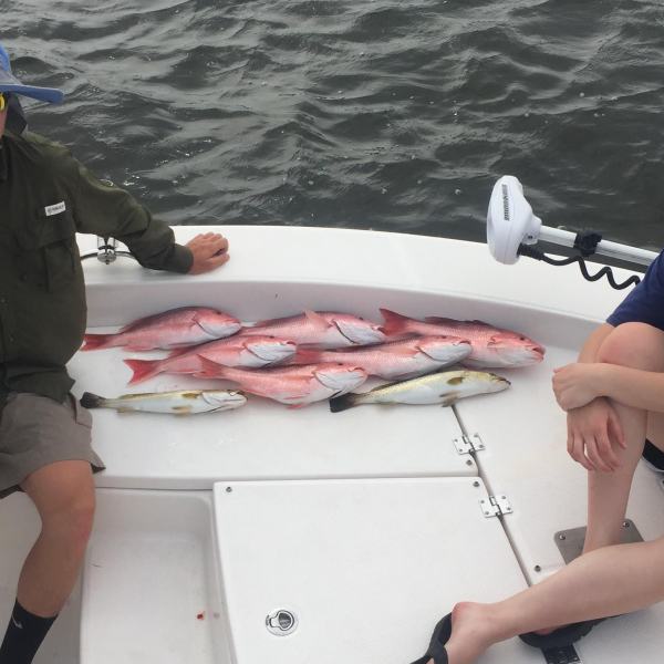 Boy and girl sitting by fish they caught on the boat
