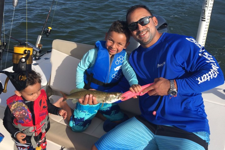 Man and small child sitting on boat holding caught fish