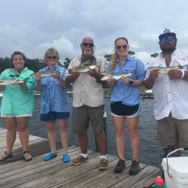 Group of fishermen and women holding their catches on the dock
