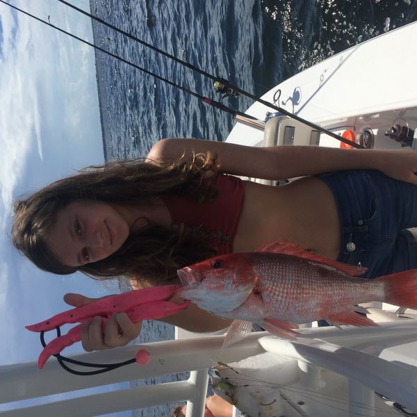 Young girl holding up red snapper she caught on fishing trip