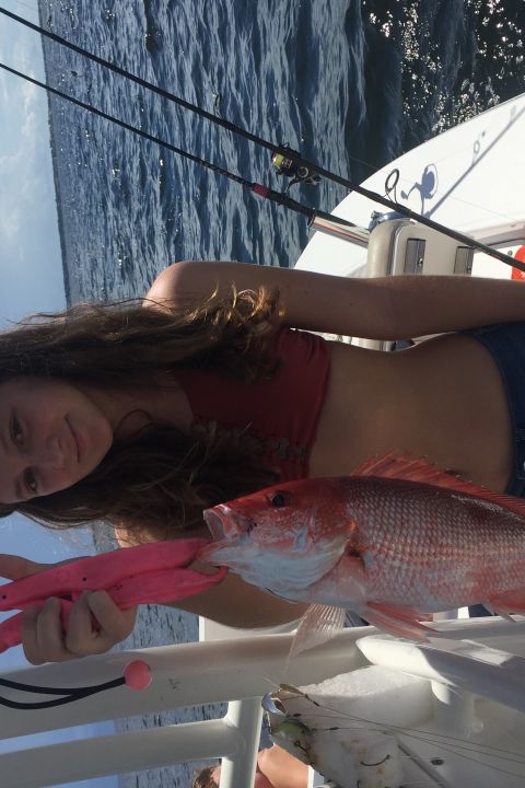 Young girl holding up red snapper she caught on fishing trip