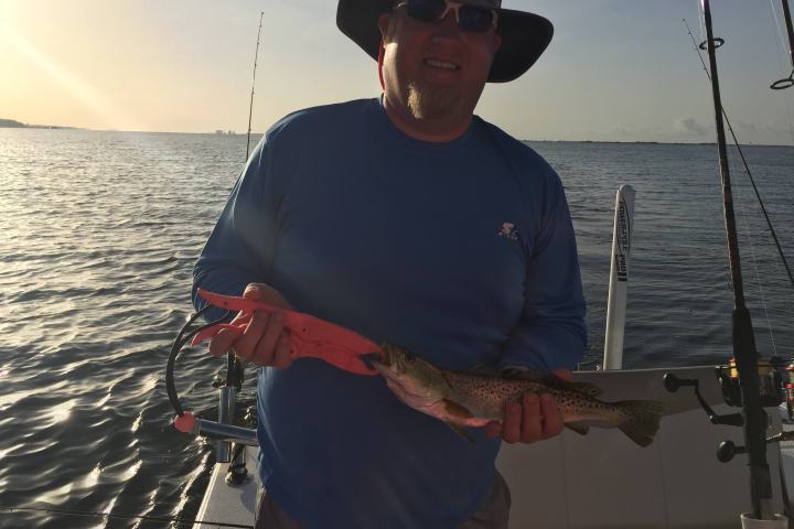 Man holding up fish during sunset boating trip