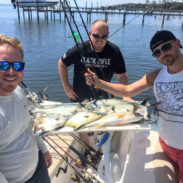 Group of men standing around fish they caught on the boat