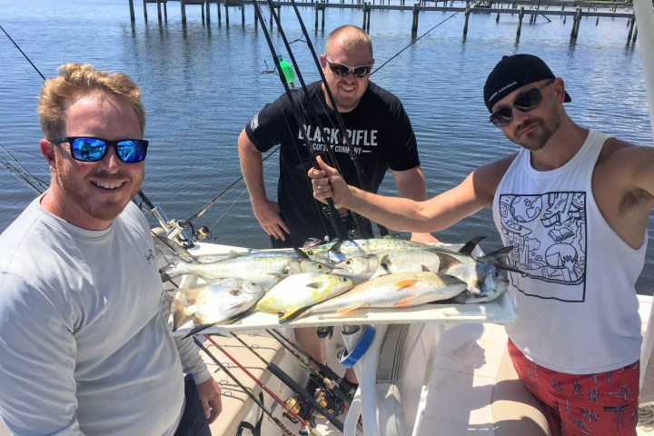 Group of men standing around fish they caught on the boat