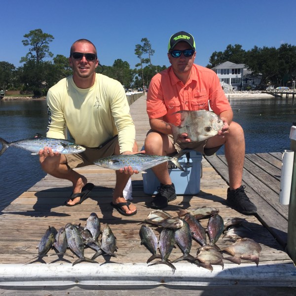 Two men standing on dock showing off their fish they caught