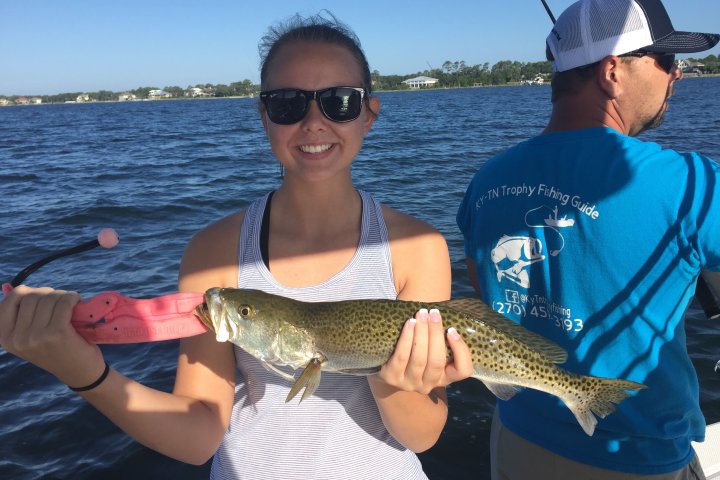 Woman holding up fish she caught on boat