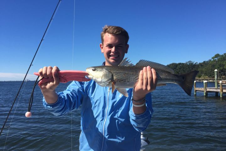 Boy holding up fish he just caught