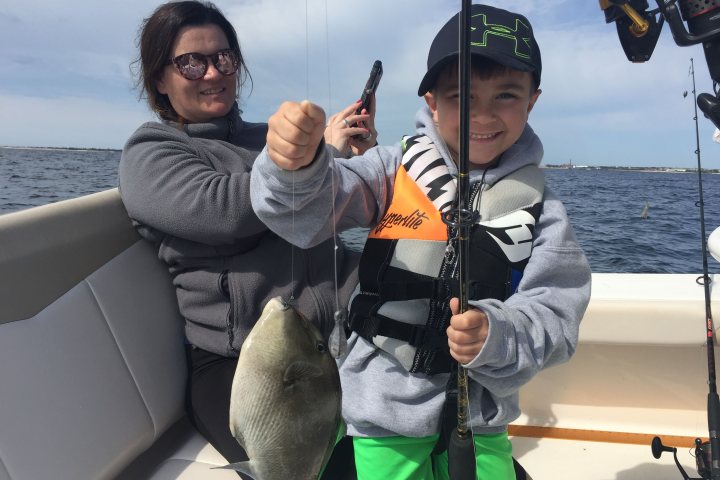 Little boy smiling at camera while holding up fish