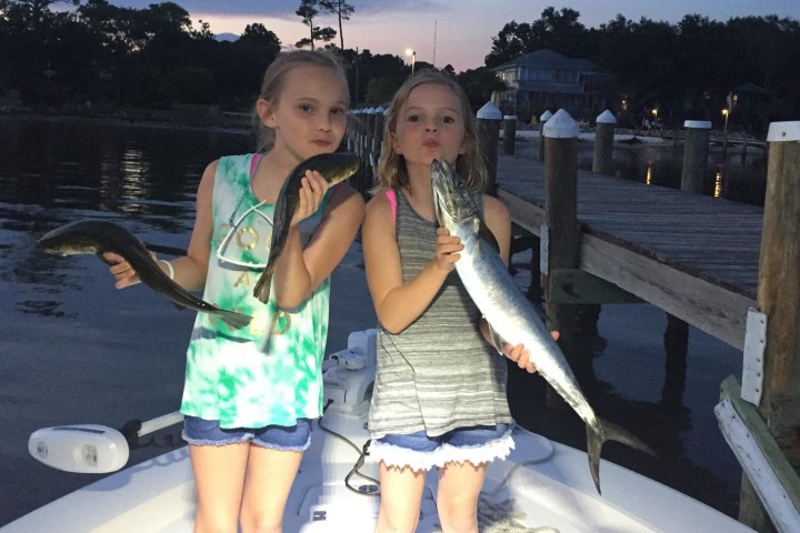 Little girls holding fish acting like they are kissing them
