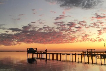 pier extending into water during sunset