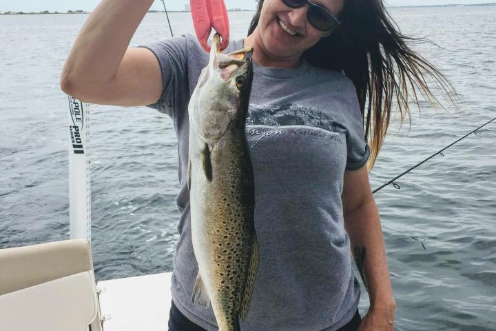 Woman holding up Spanish mackerel she just caught on the boat