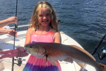 a person holding a fish on a boat in a body of water